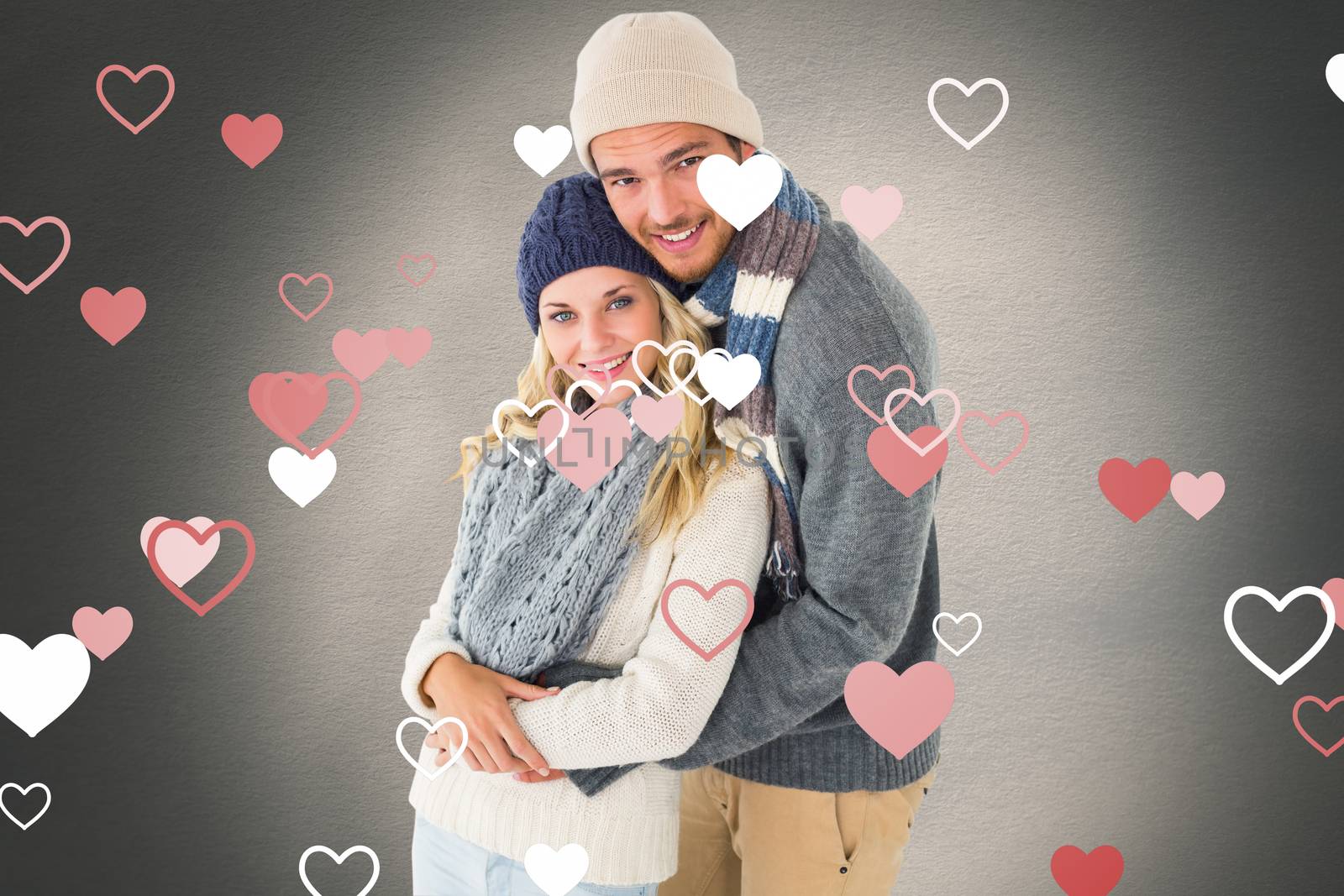 Attractive couple in winter fashion hugging against white background with vignette