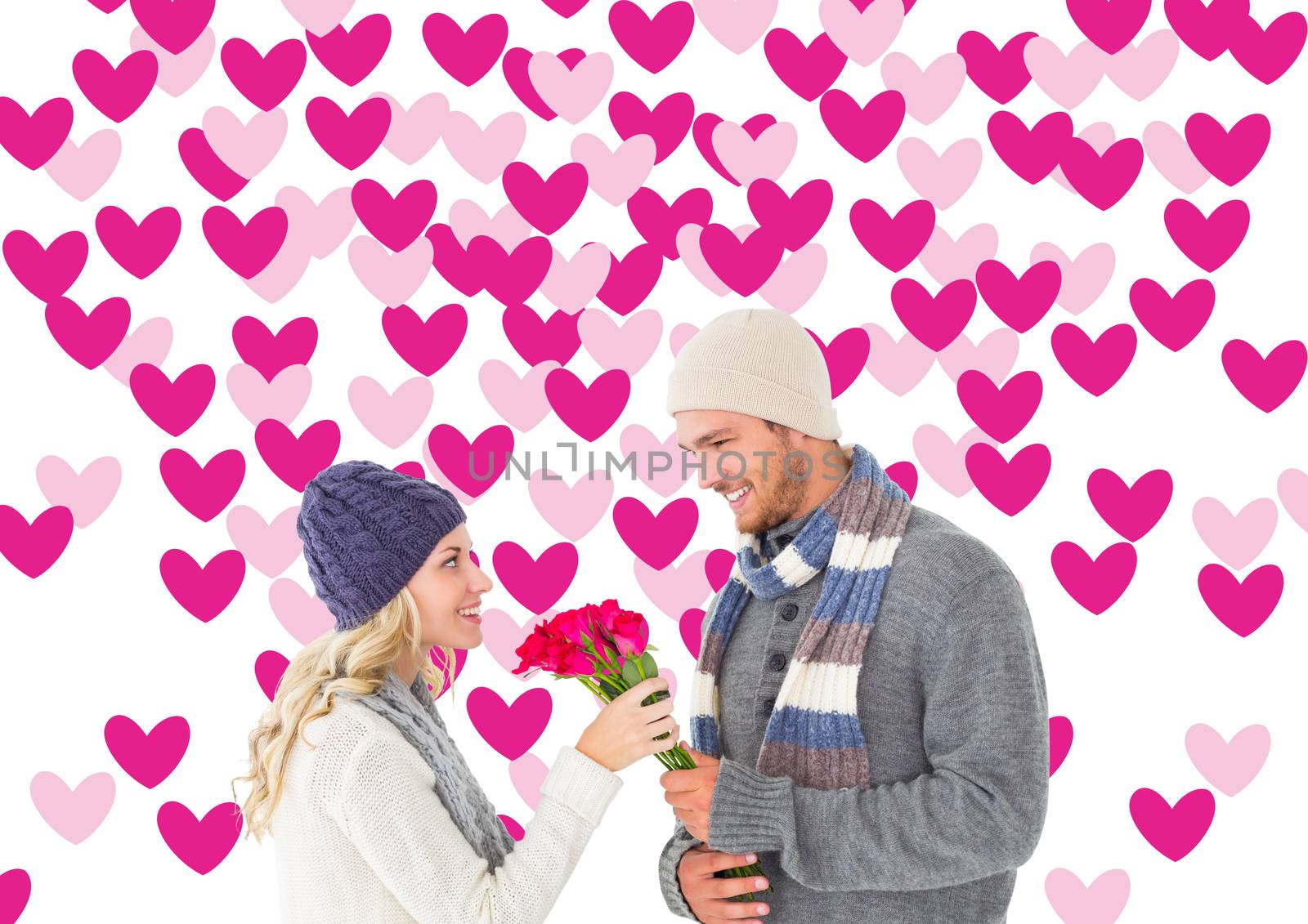 Attractive man in winter fashion offering roses to girlfriend against valentines day pattern