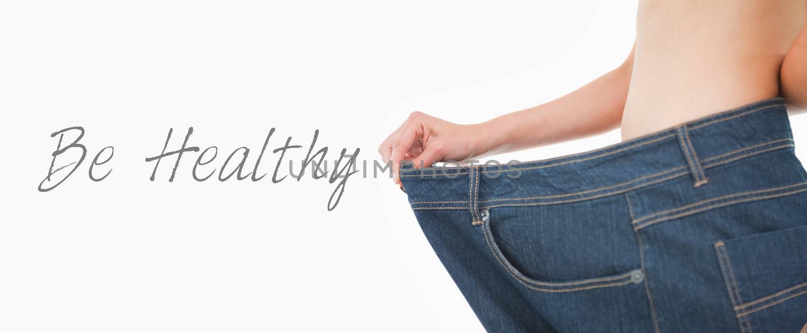 Close up of a woman belly in too big pants against white background