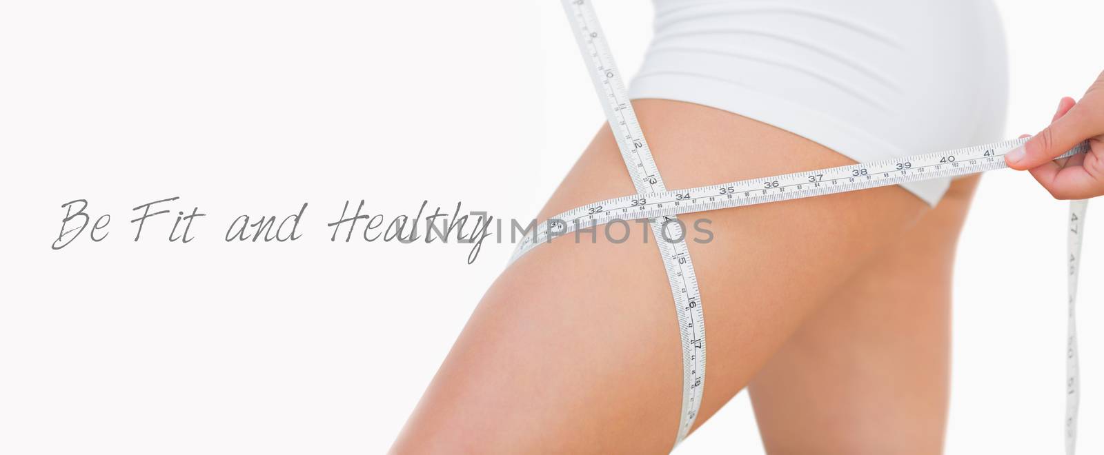 Midsection of woman measuring thigh over white background