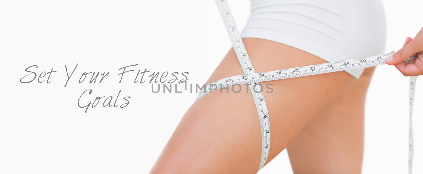 Midsection of woman measuring thigh over white background
