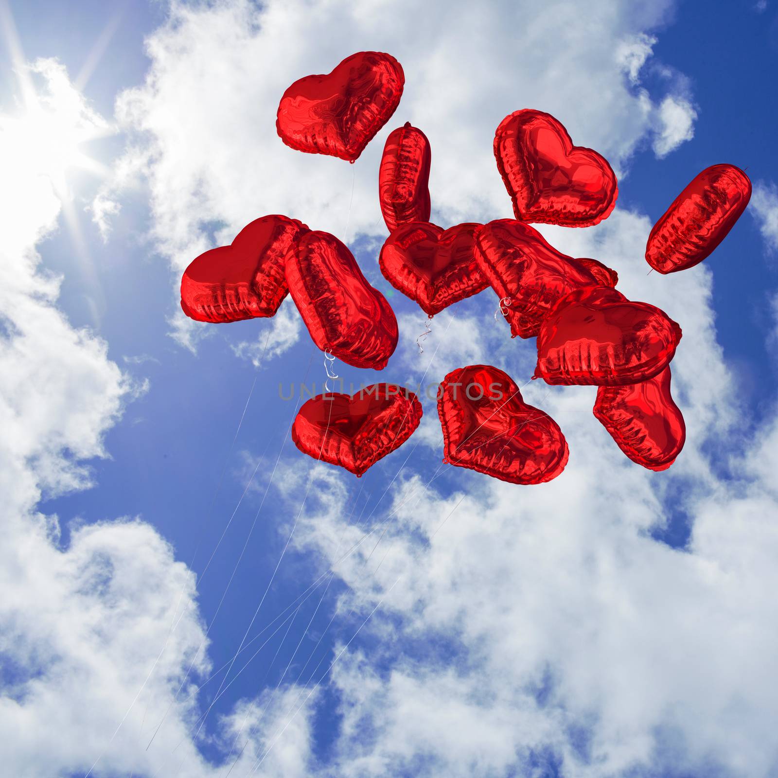Heart balloons against bright blue sky with clouds