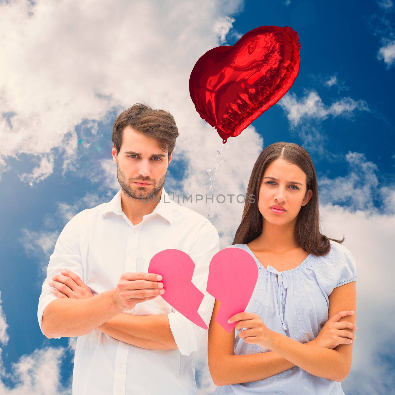 Upset couple holding two halves of broken heart against bright blue sky with clouds