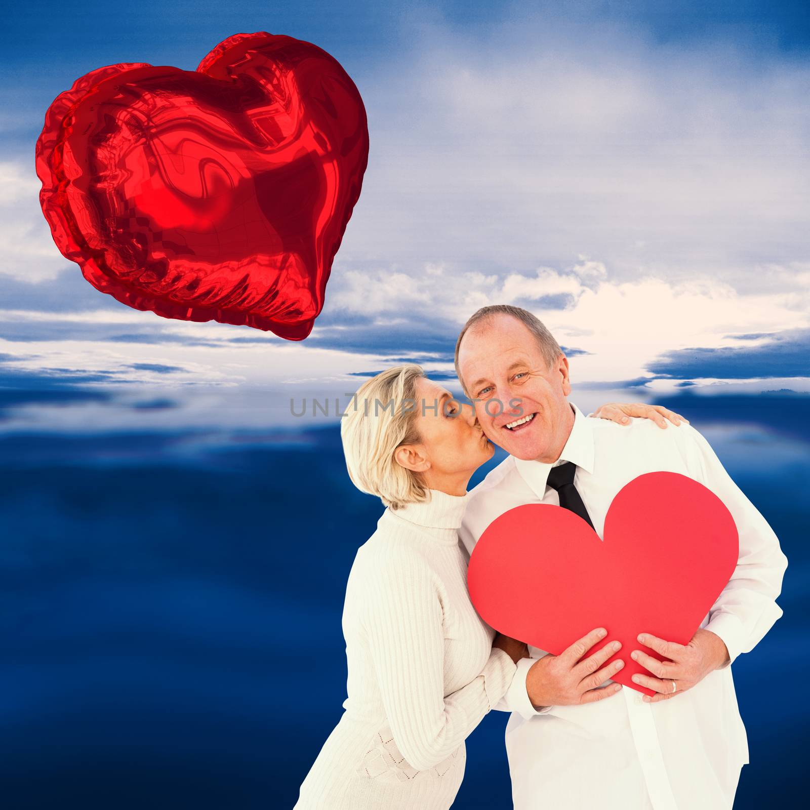Composite image of older affectionate couple holding red heart shape by Wavebreakmedia
