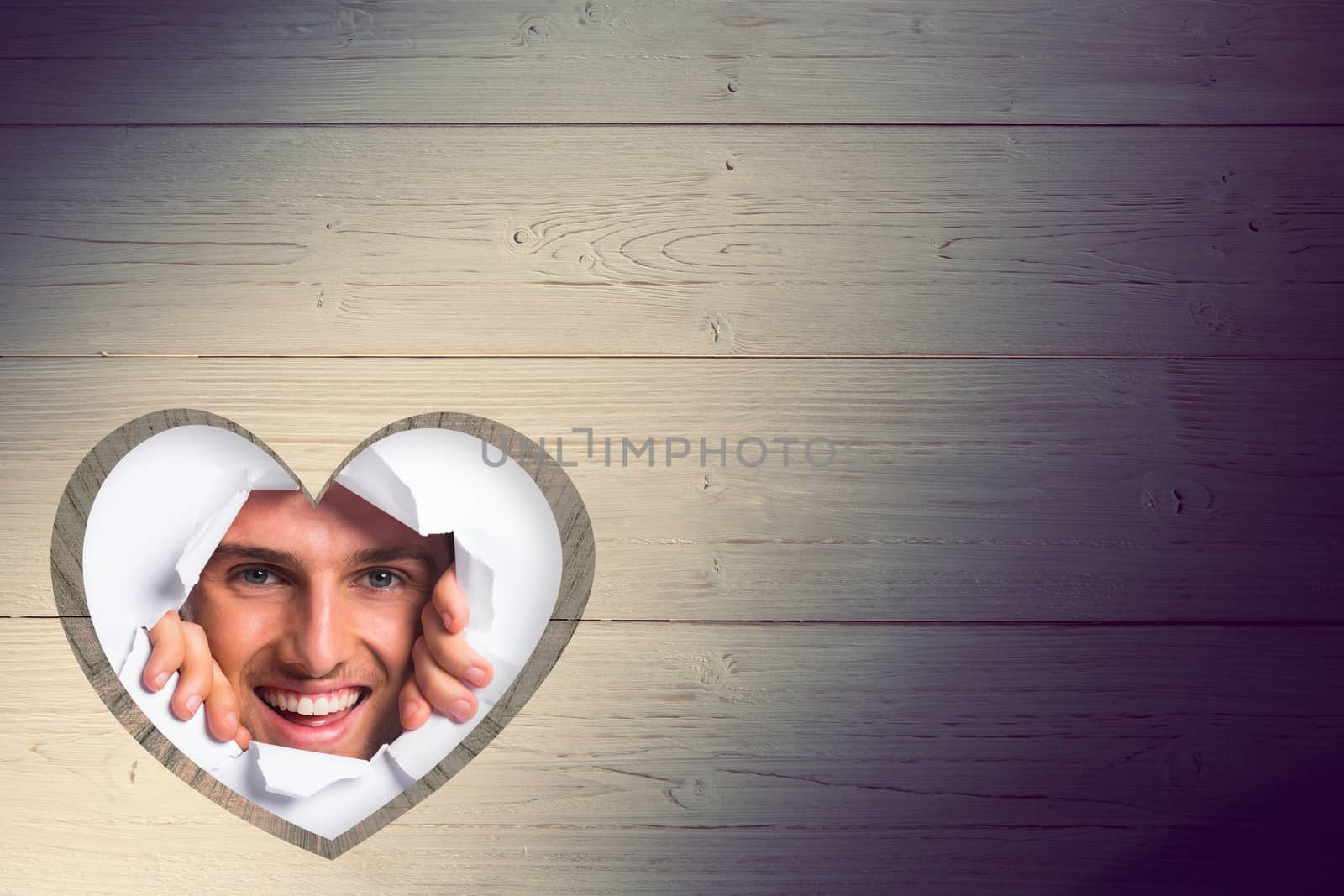 Young man looking through paper rip against heart in wood