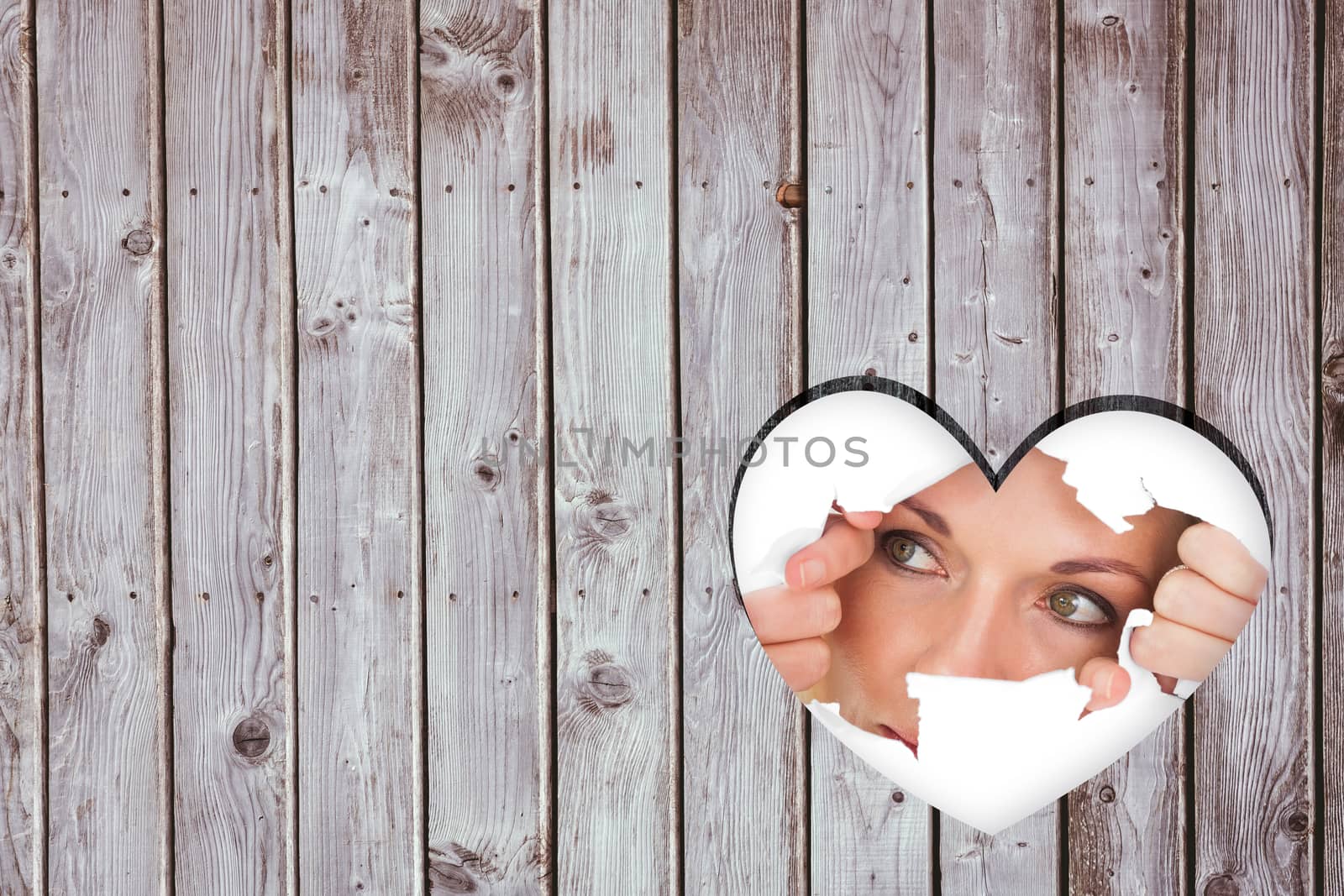 Woman looking through torn paper against heart in wood