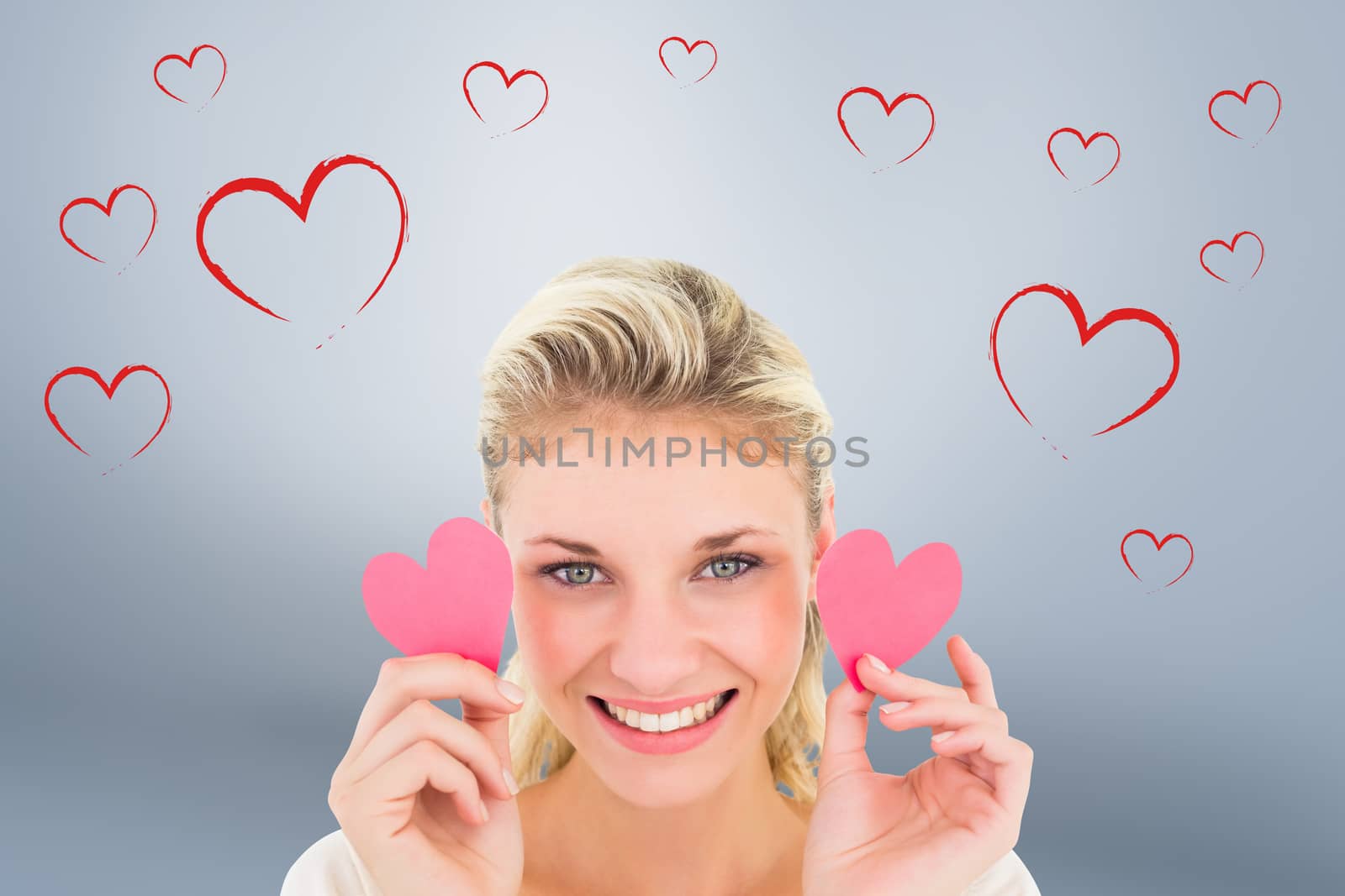 Attractive young blonde holding little hearts  against grey vignette