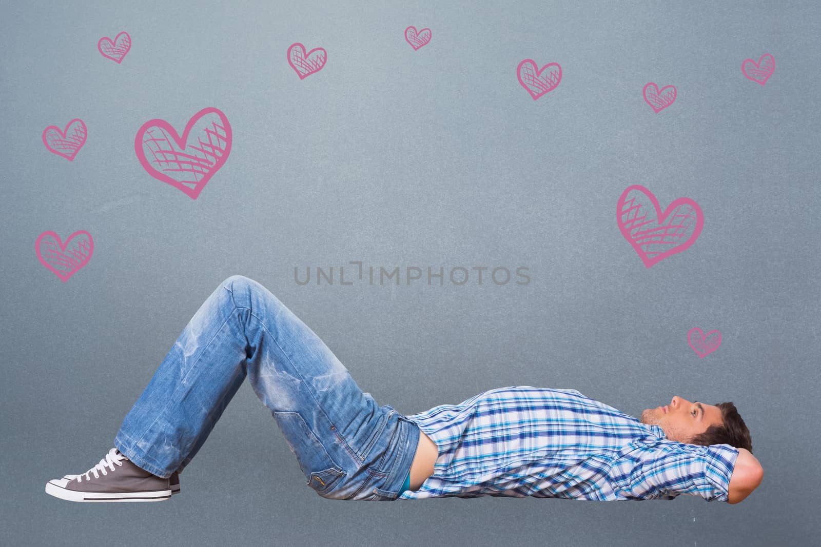 Young man lying on floor thinking against grey