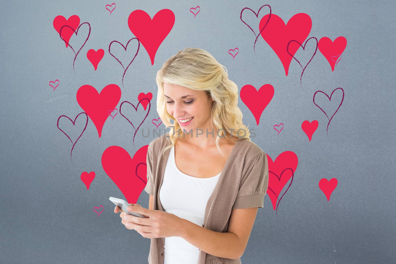 Attractive blonde using her smartphone against grey