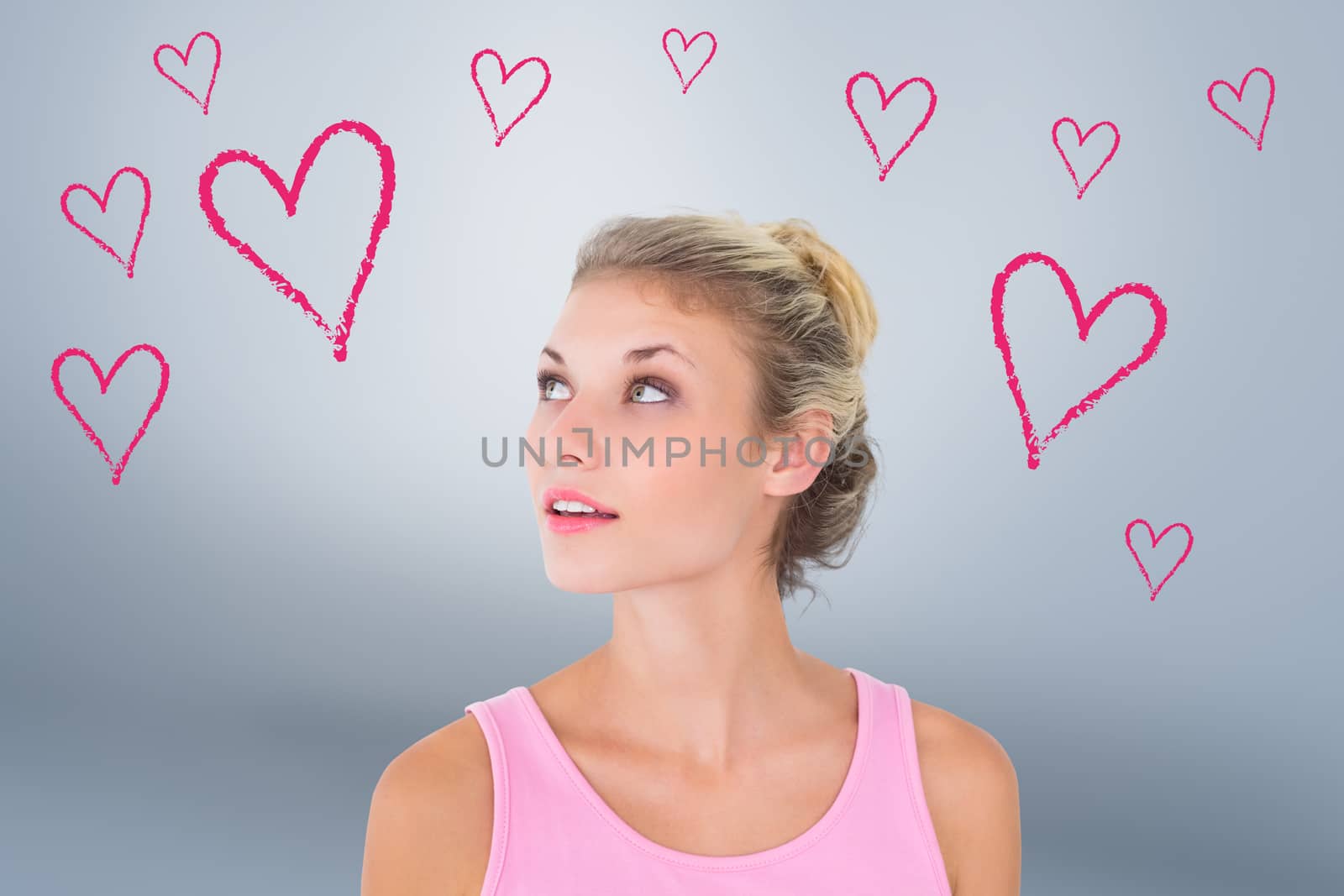 Composite image of pretty young blonde in pink looking up by Wavebreakmedia
