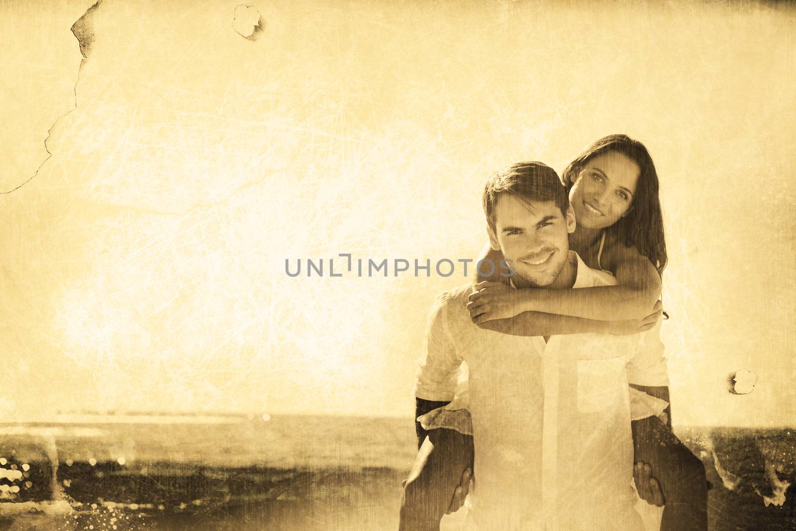 Smiling man giving girlfriend a piggy back looking at camera against grey background