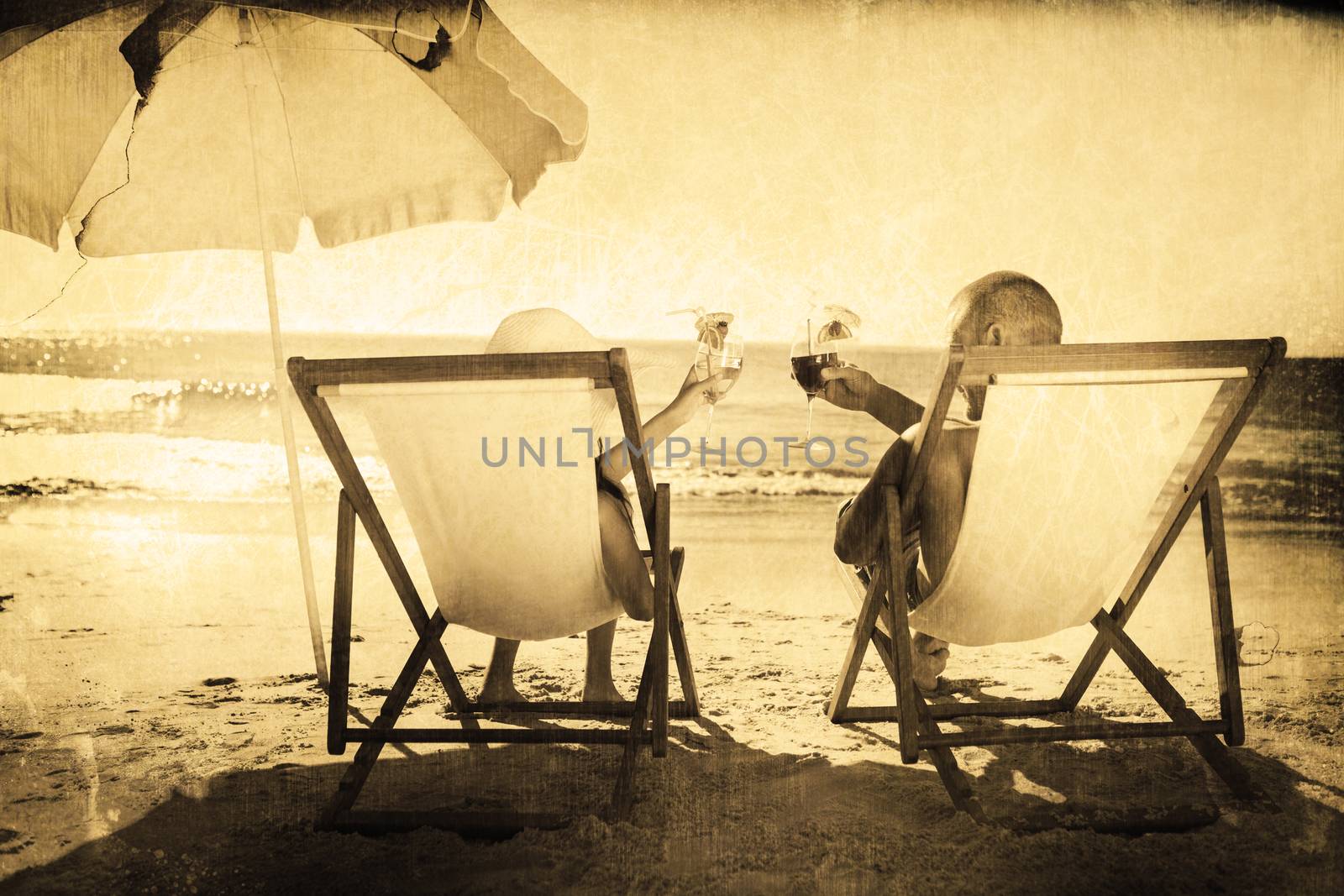 Composite image of happy couple drinking cocktails while relaxing on their deck chairs by Wavebreakmedia