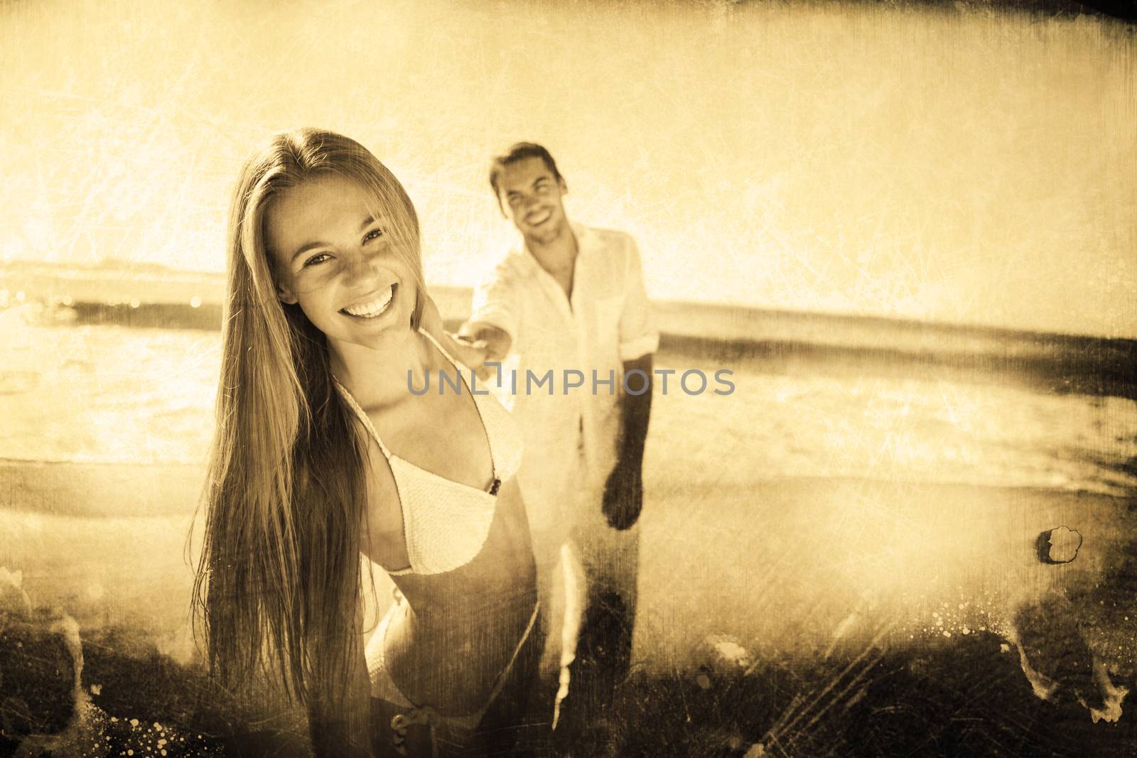 Woman smiling at camera with boyfriend holding her hand against grey background