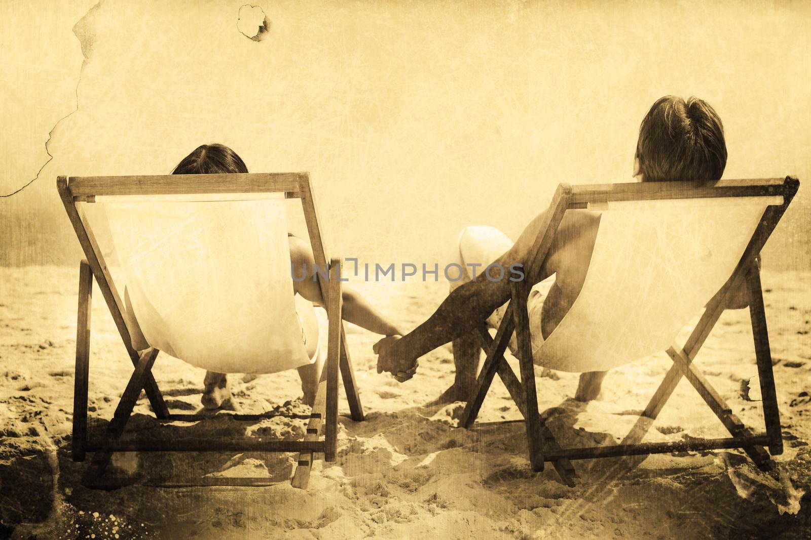 Grey background against couple lying on deck chairs