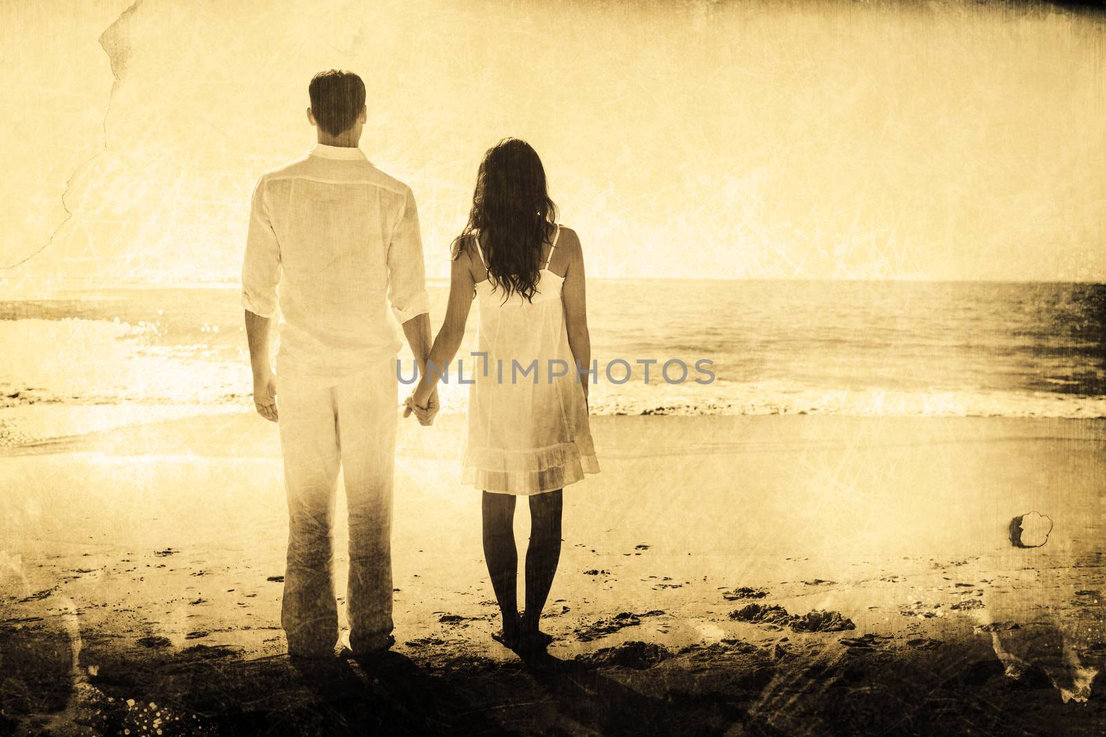 Composite image of attractive couple holding hands and watching the waves by Wavebreakmedia