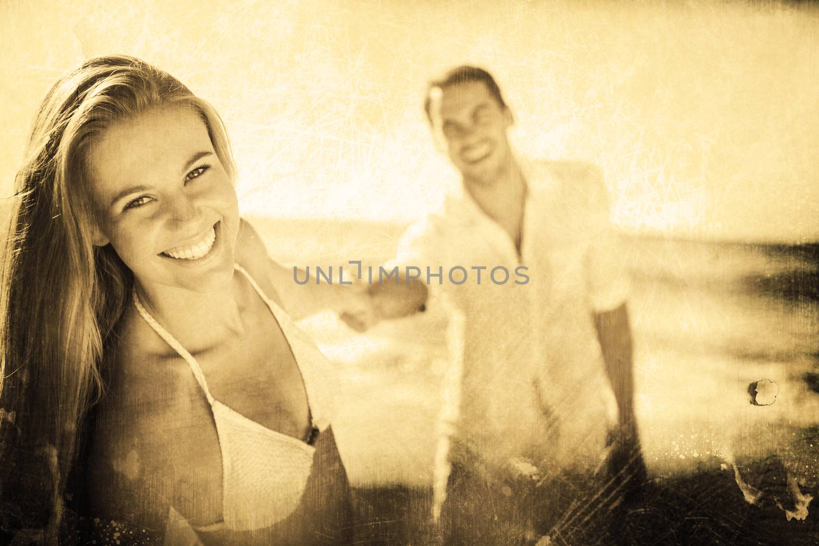 Pretty woman smiling at camera with boyfriend holding her hand against grey background