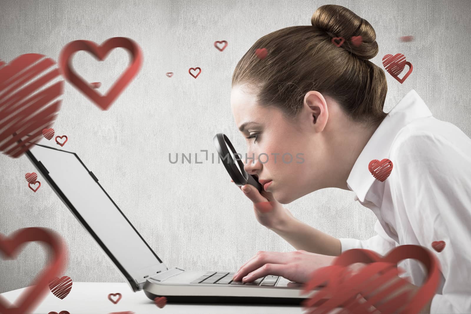 Businesswoman typing and looking through magnifying glass against white and grey background