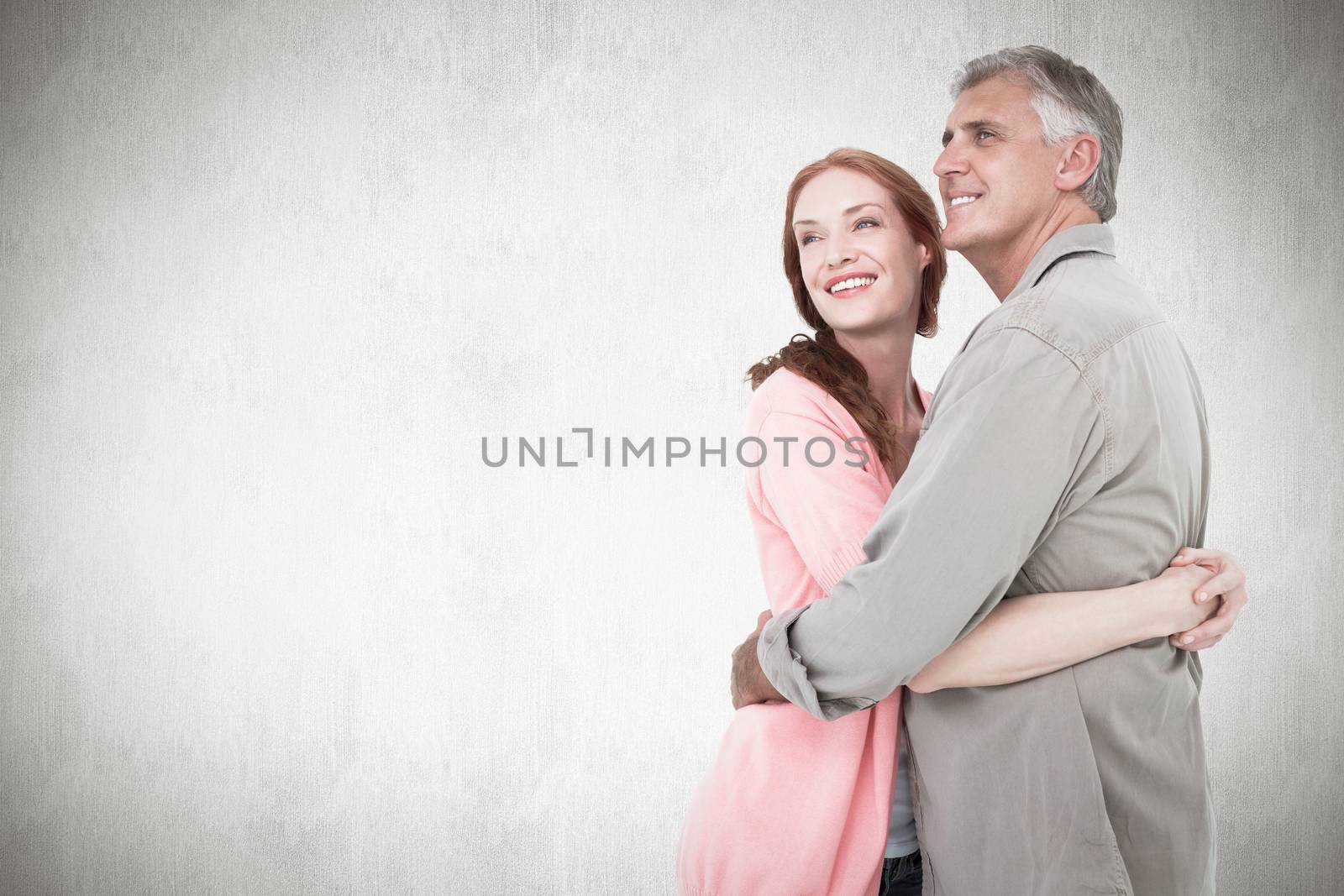 Casual couple hugging and smiling against white background