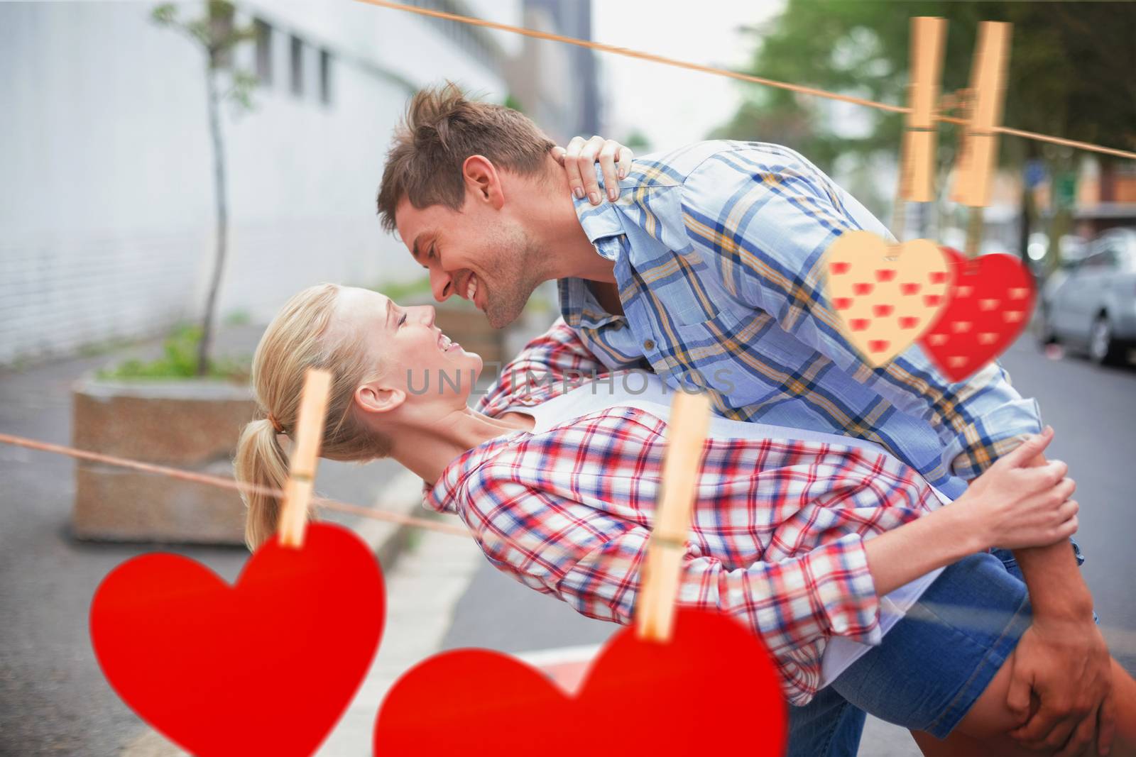 Hip romantic couple dancing in the street against hearts hanging on the line