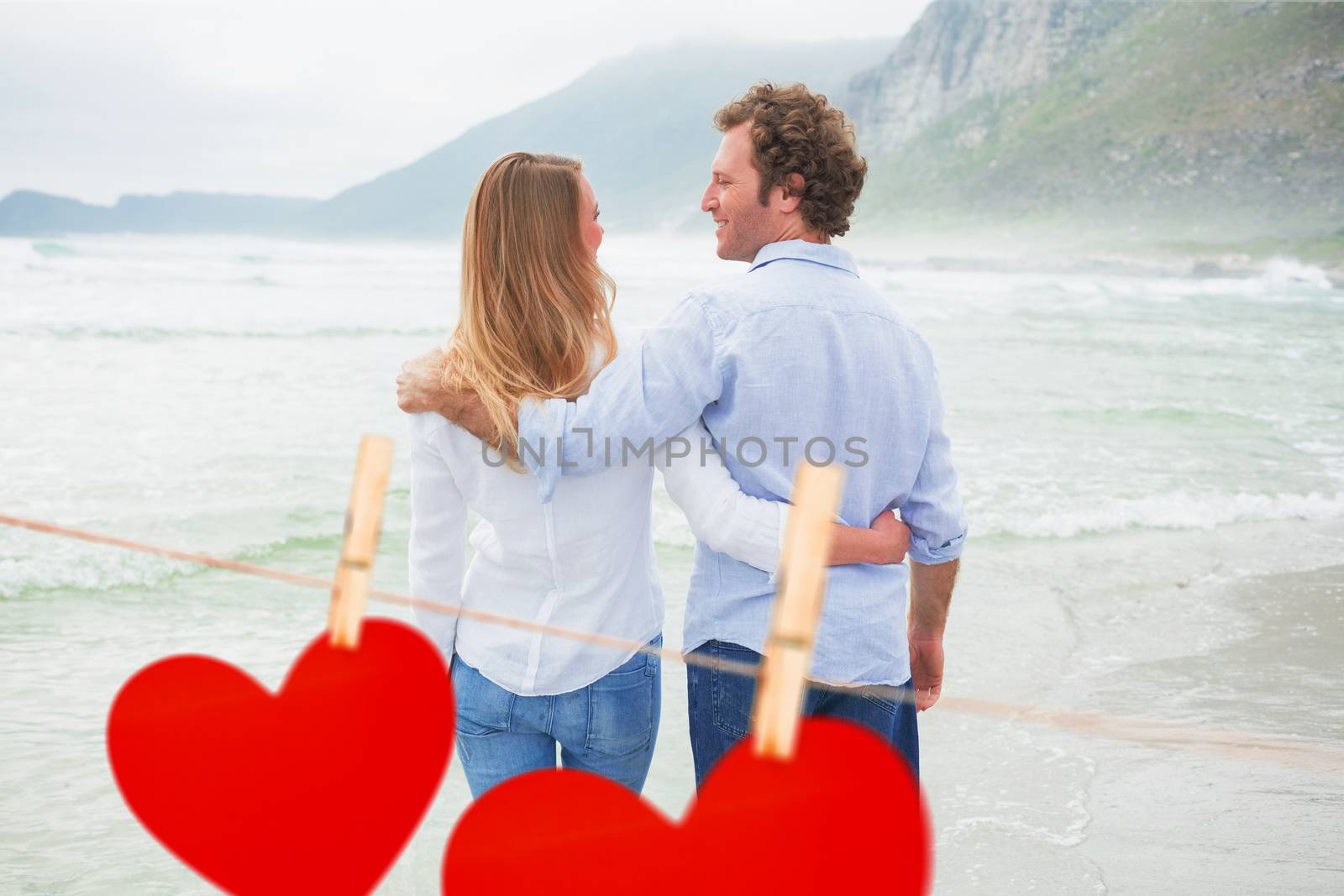 Rear view of a romantic couple at beach against hearts hanging on a line