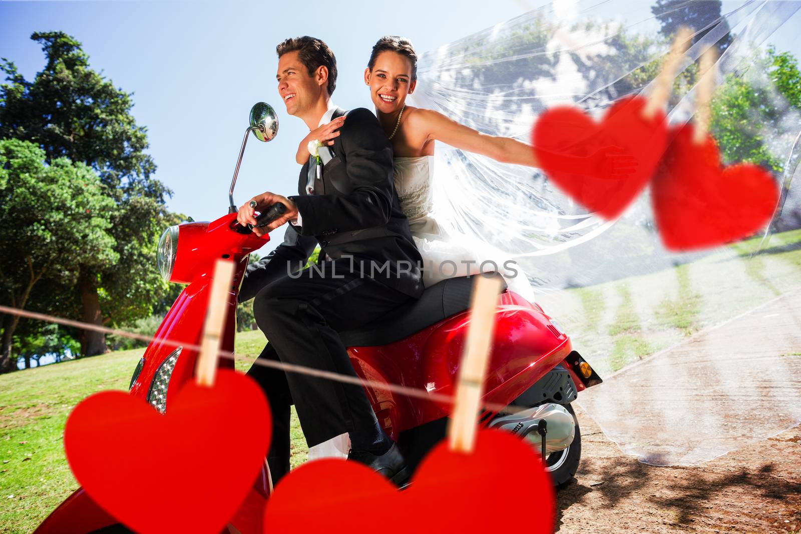 Newlywed couple enjoying scooter ride against hearts hanging on a line