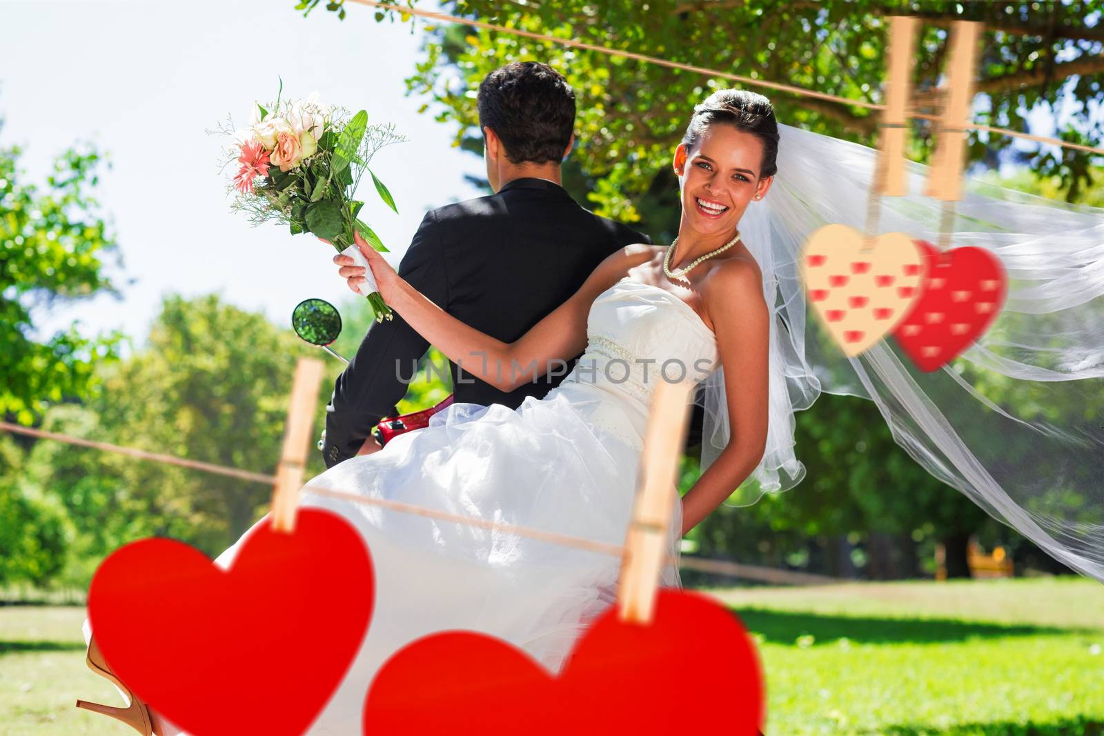 Newlywed couple sitting on scooter in park against hearts hanging on the line