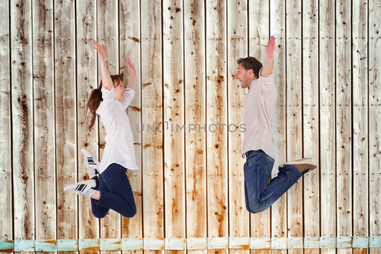 Couple jumping in the air against faded pine wooden planks