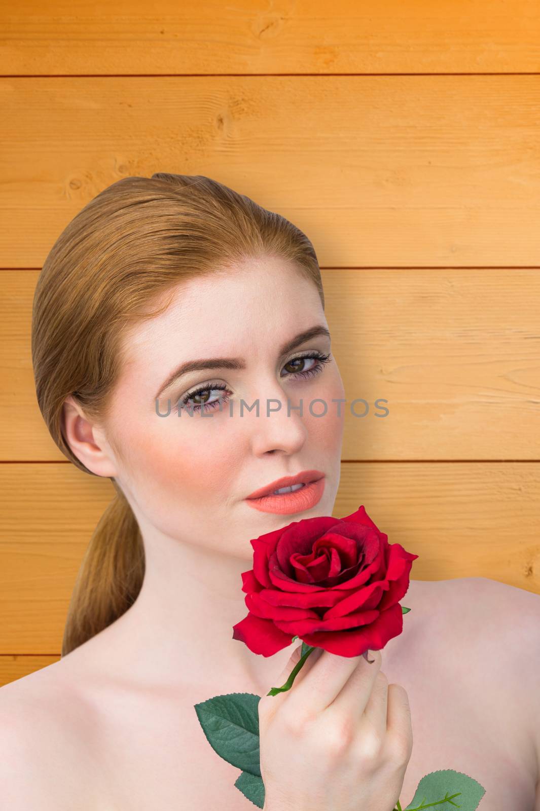 Composite image of beautiful redhead posing with red rose by Wavebreakmedia