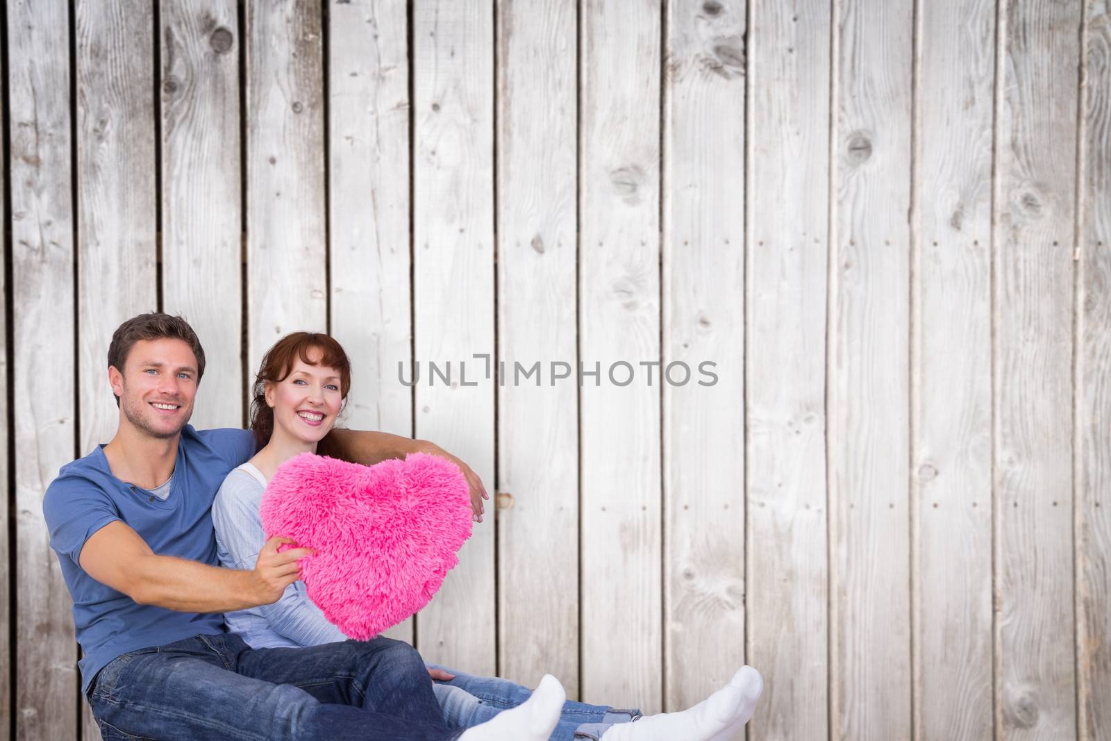 Couple holding a large heart against wooden planks