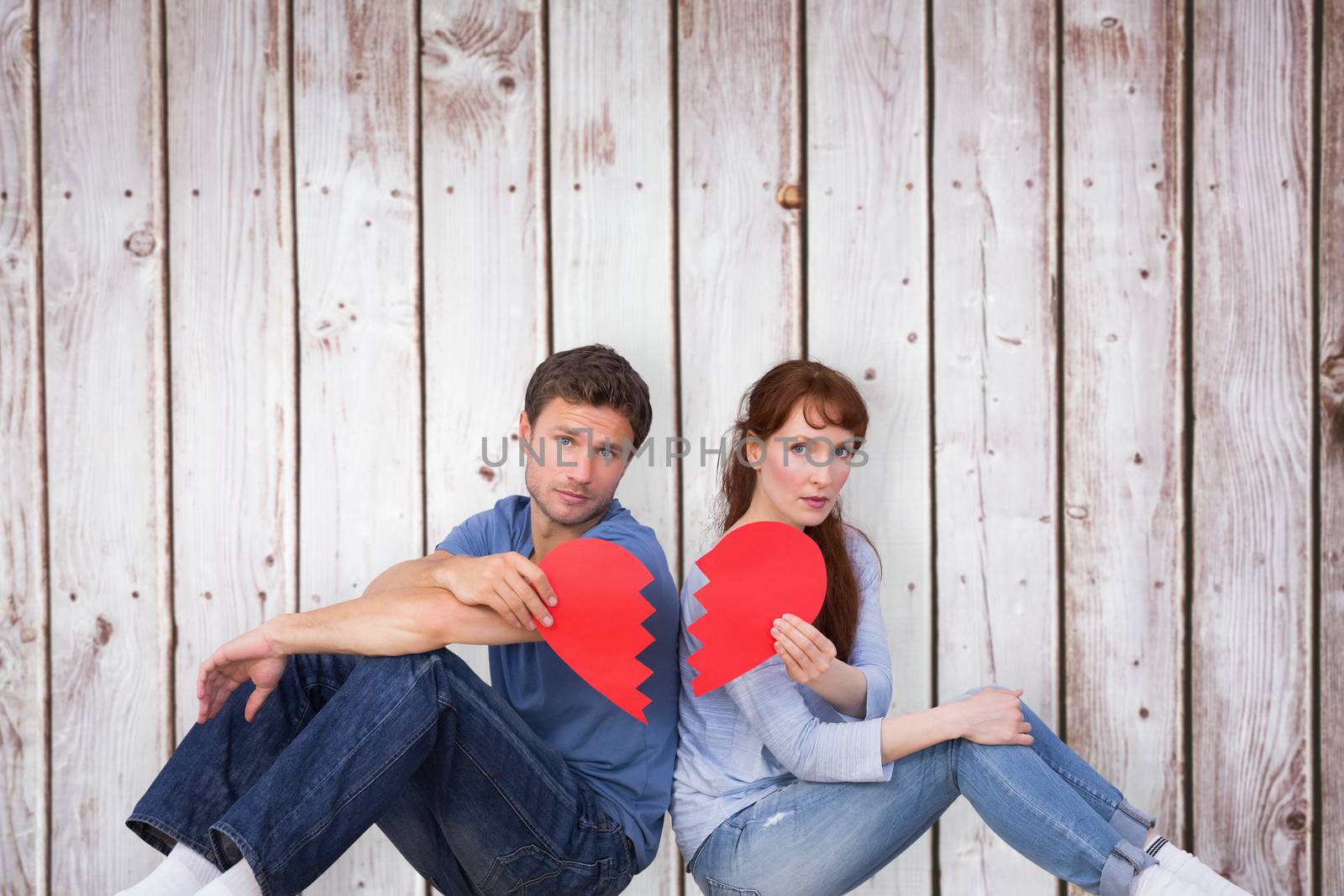 Couple holding a broken heart against wooden planks