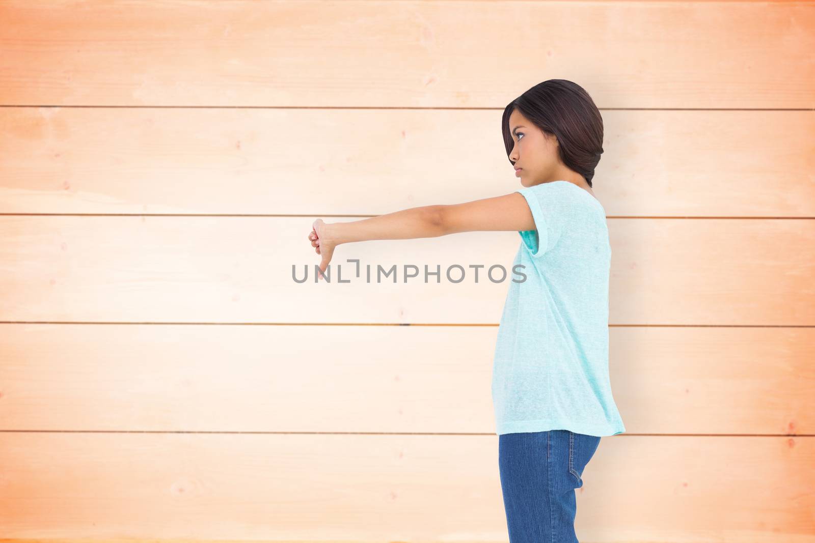 Disappointed brunette giving thumbs down against wooden planks