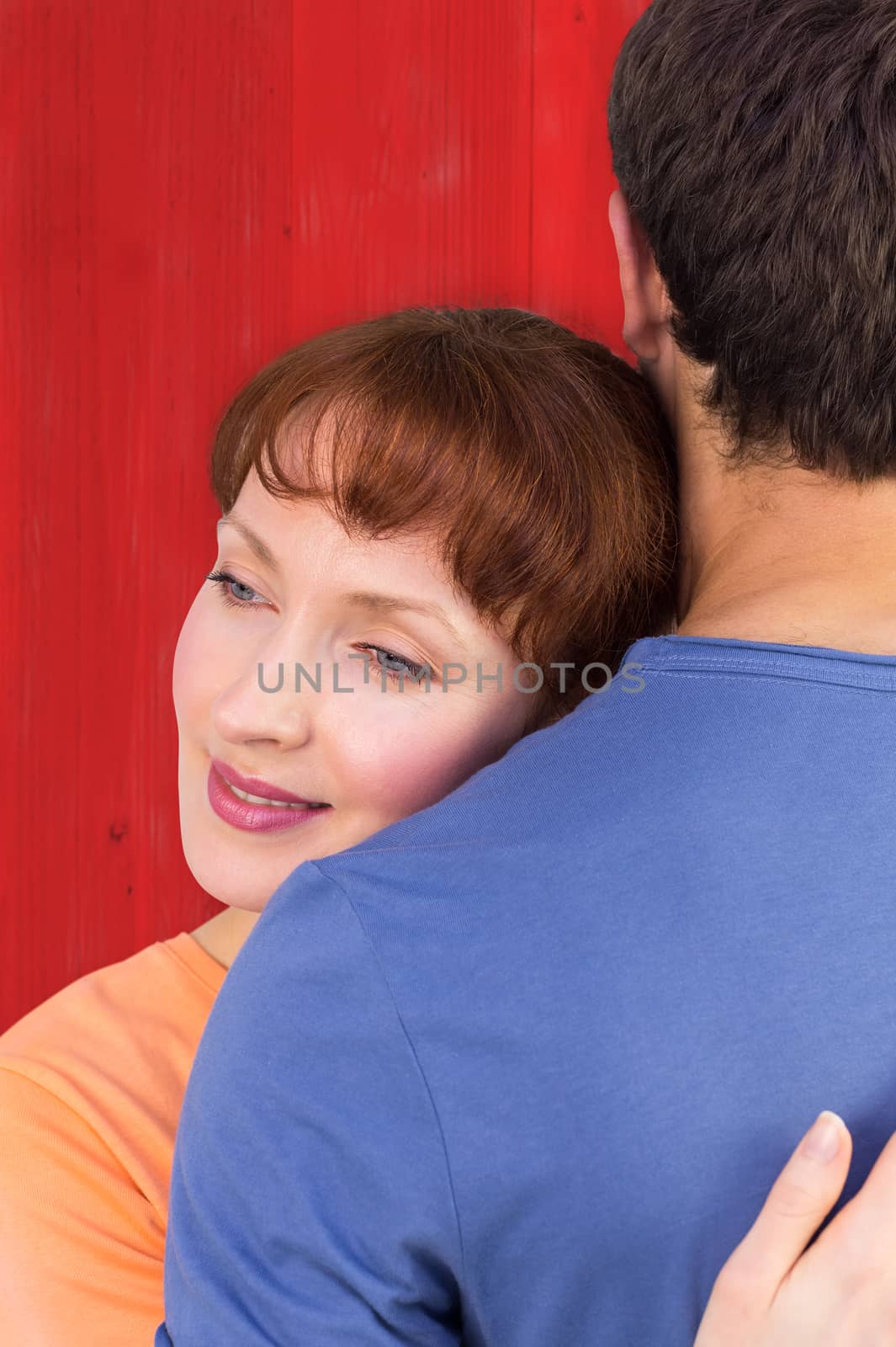 Happy couple hugging one another against red wooden planks