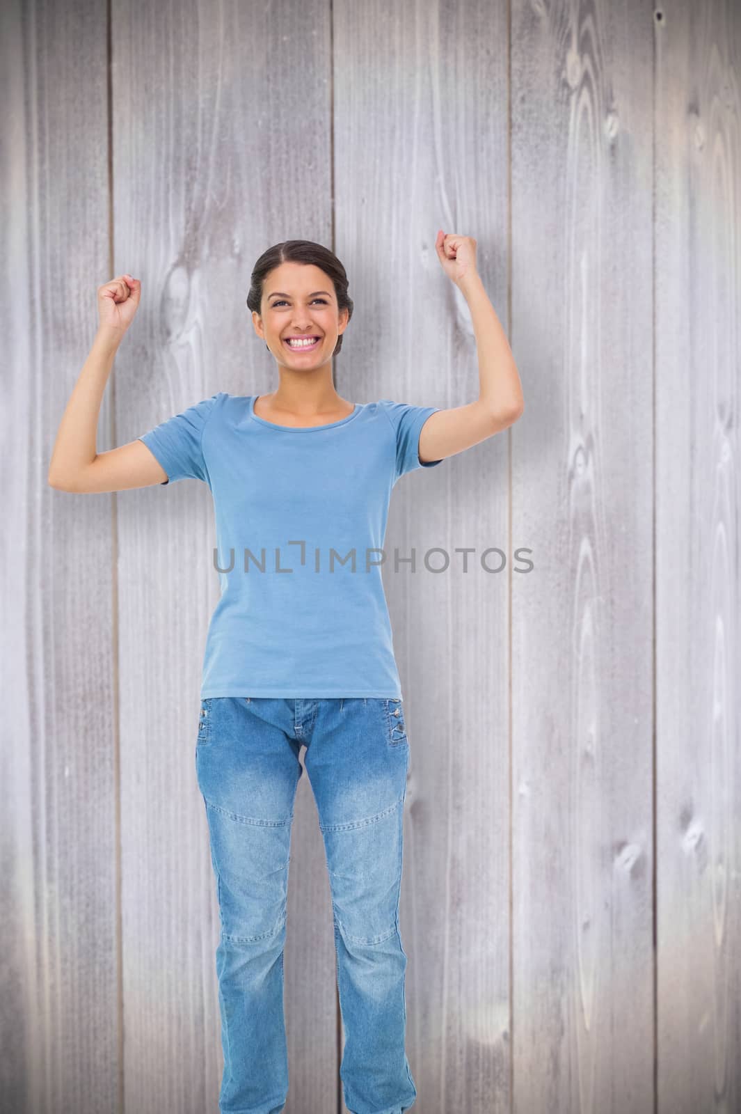 Happy brunette cheering against wooden planks background