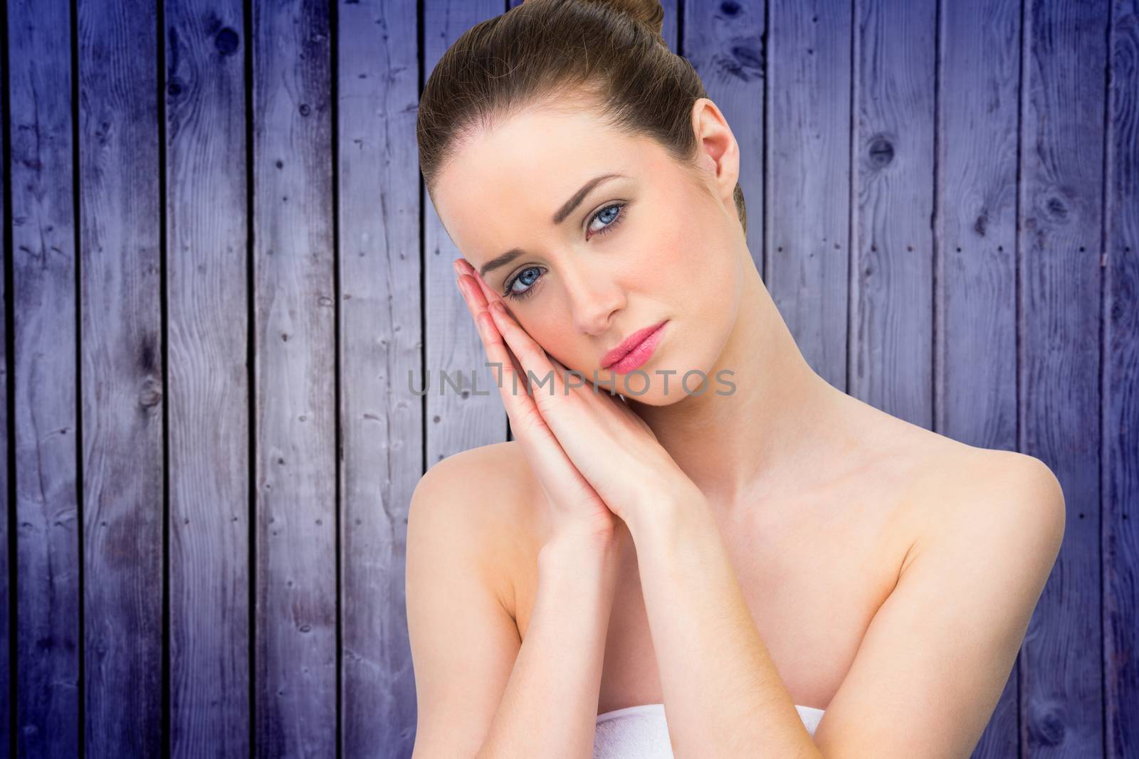 Beautiful brunette with hands at face against wooden planks background