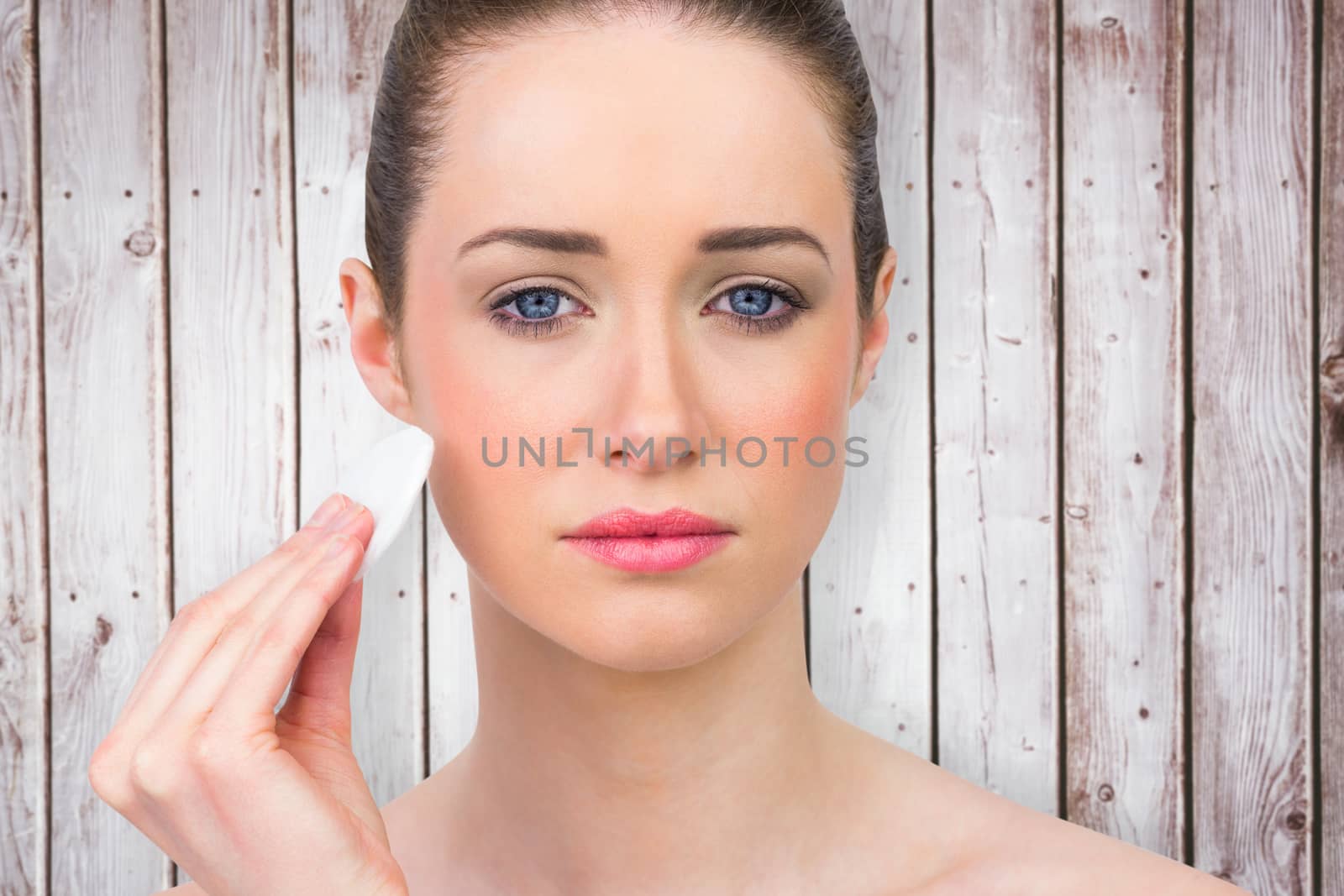 Beautiful brunette using powder puff against wooden planks