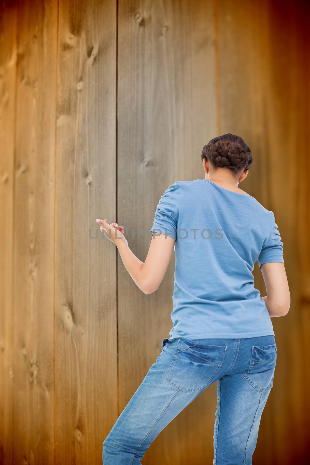 Pretty brunette playing air guitar against wooden planks background