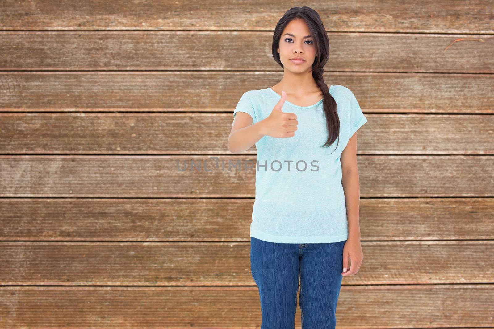 Composite image of happy brunette giving thumbs up by Wavebreakmedia