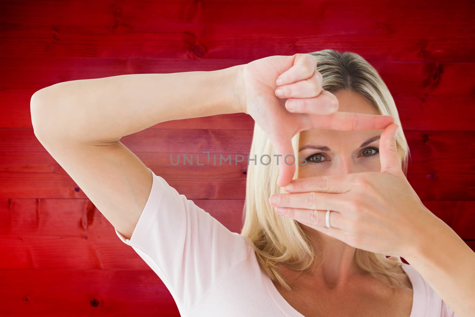 Happy blonde framing with her hands against wooden planks background