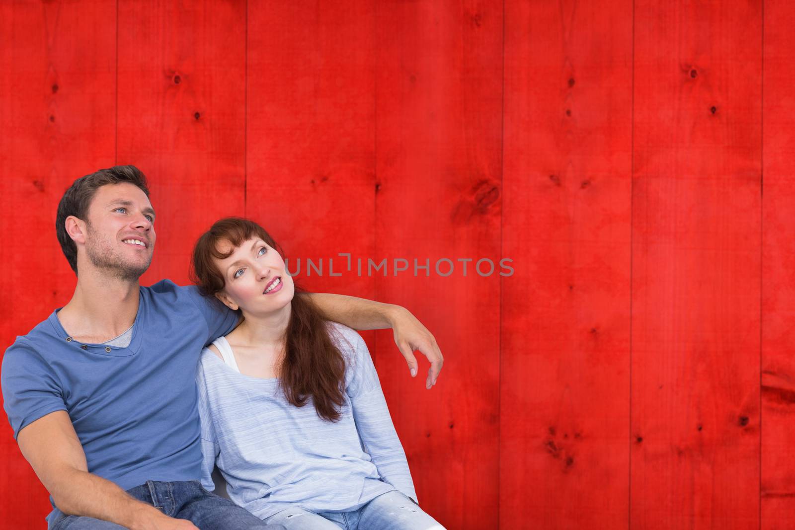 Couple sitting on floor together against bright red wooden planks