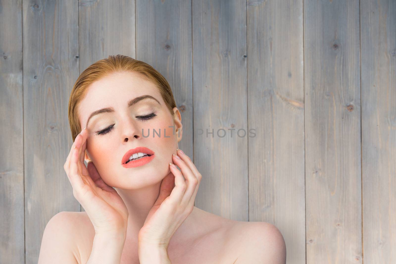 Beautiful redhead posing with hands against pale grey wooden planks