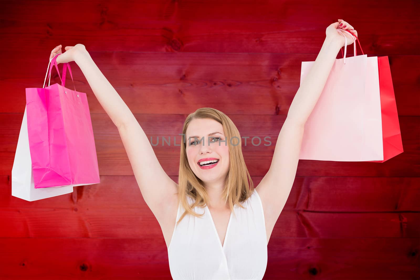 Composite image of young woman holding up shopping bags by Wavebreakmedia