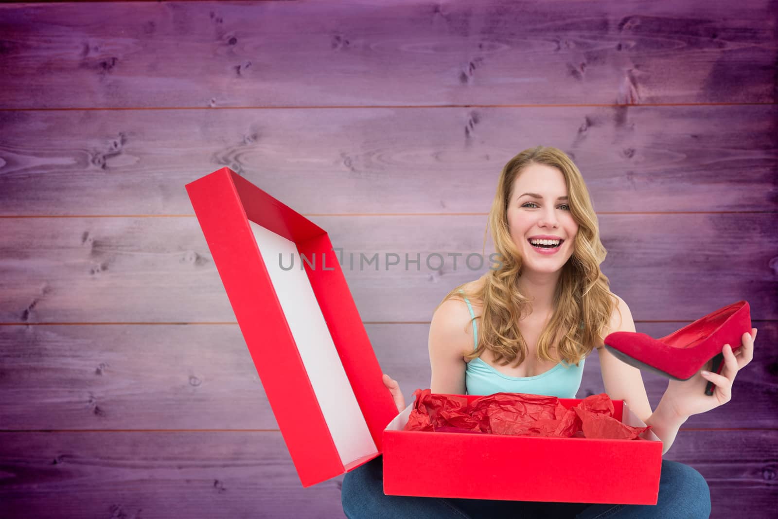 Smiling young woman showing her new shoes against wooden planks background