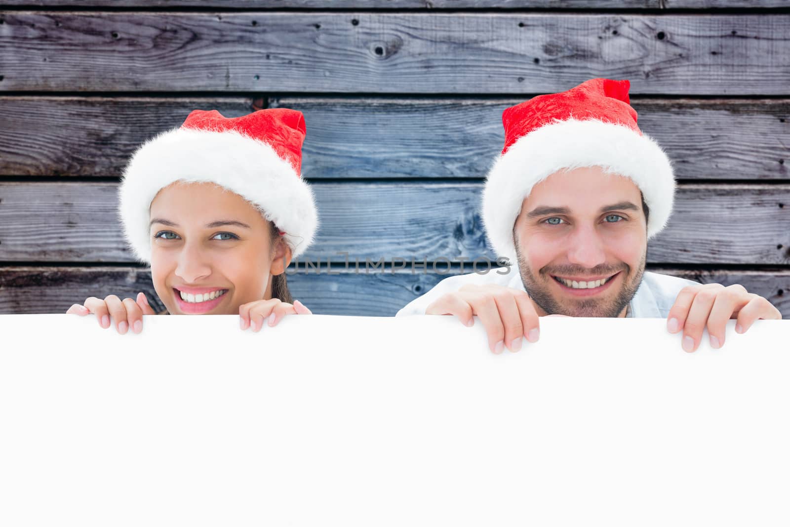 Festive young couple smiling at camera against grey wooden planks