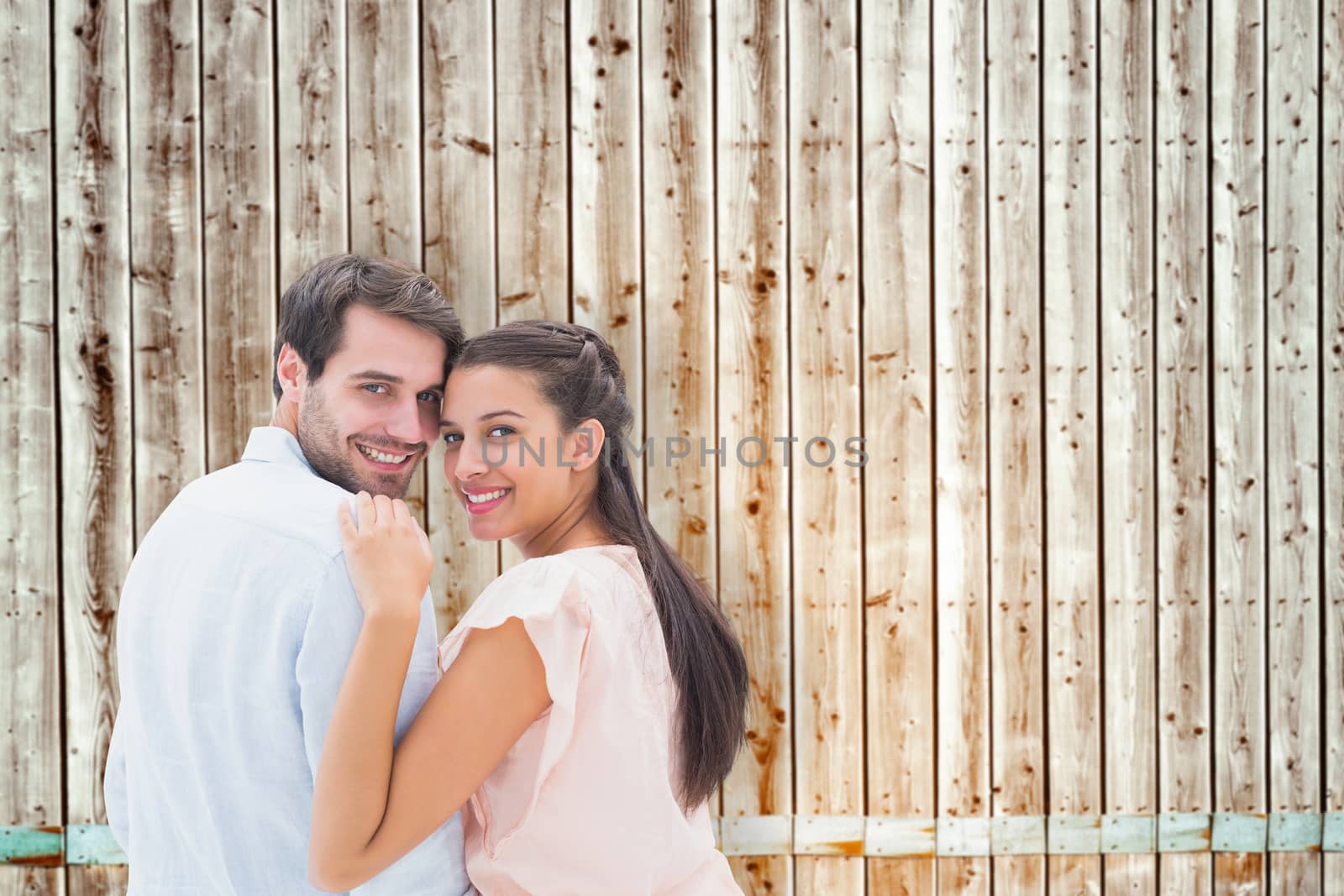 Attractive young couple smiling at camera against faded pine wooden planks