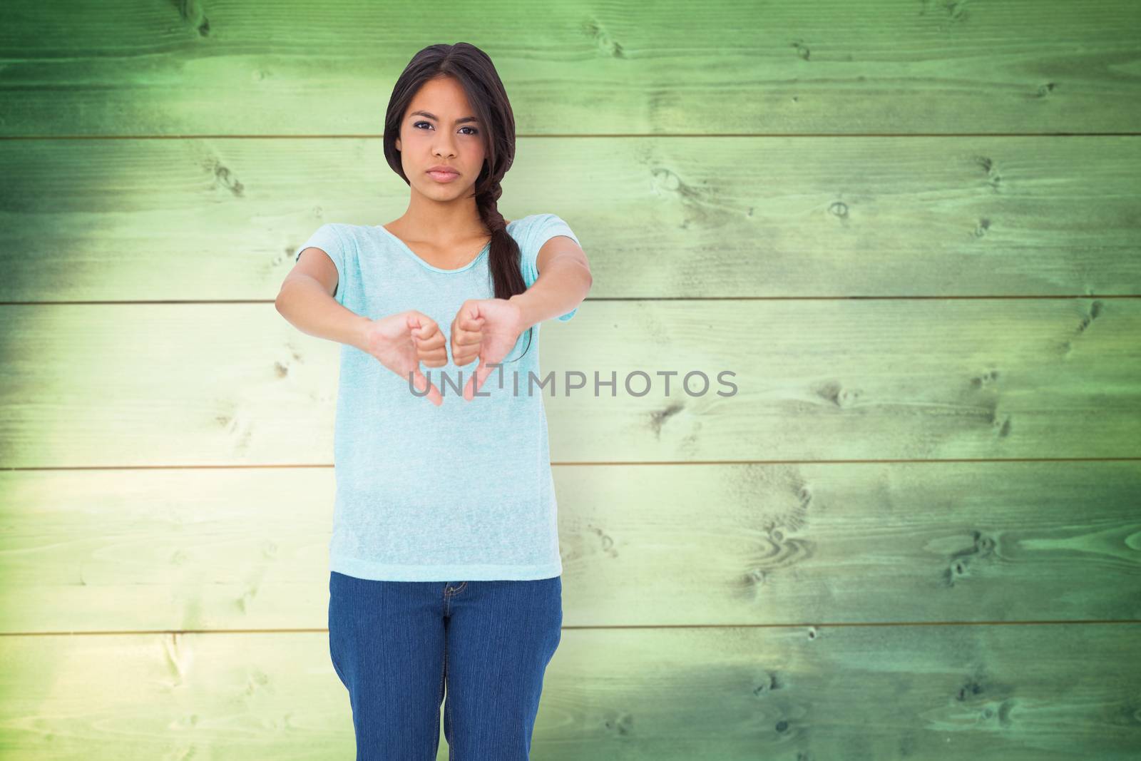 Disappointed brunette giving thumbs down against wooden planks