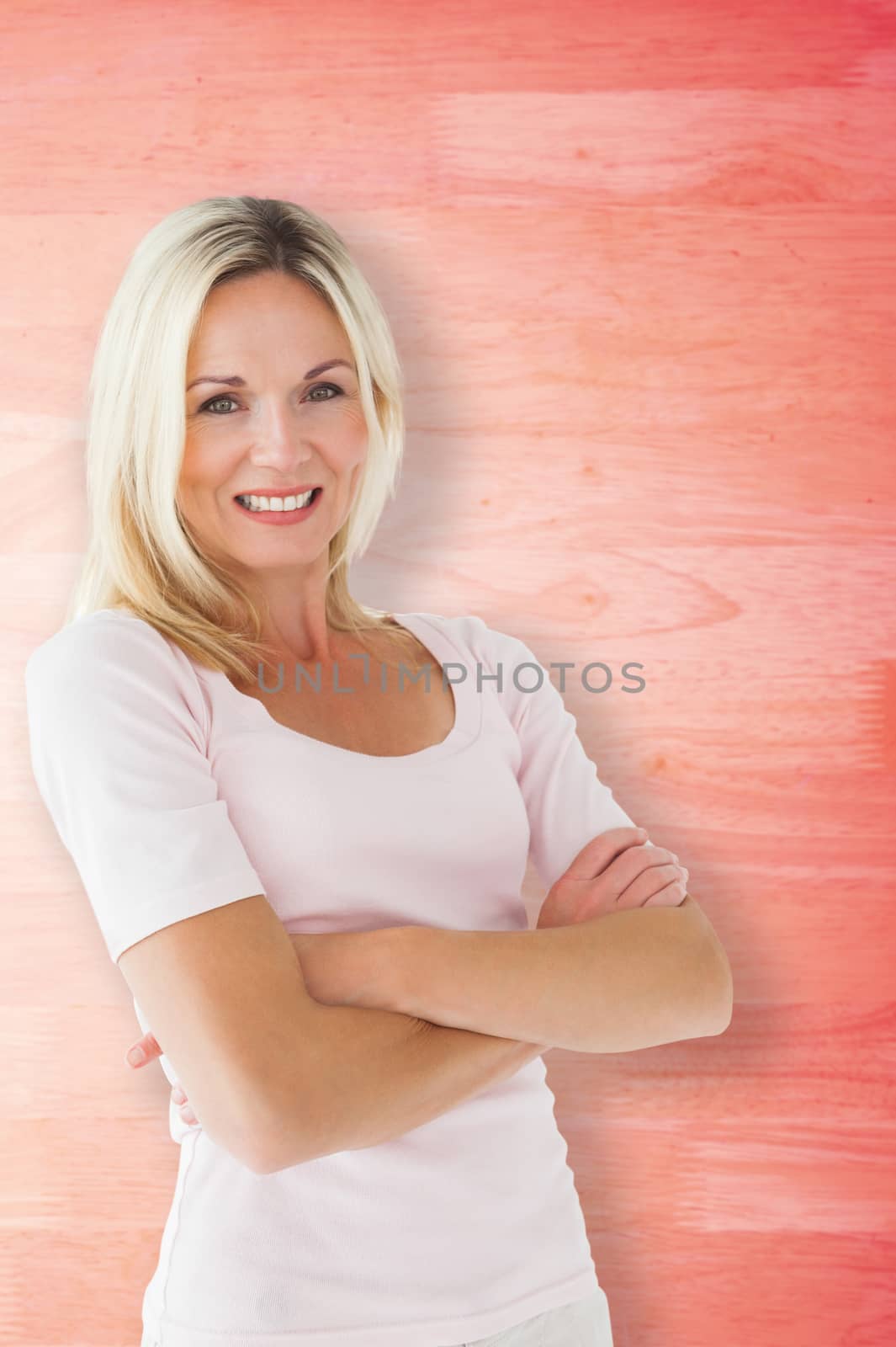Happy blonde smiling with arms crossed against red faded wooden planks