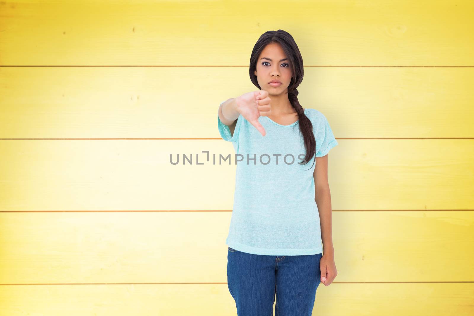 Disappointed brunette giving thumbs down against wooden planks