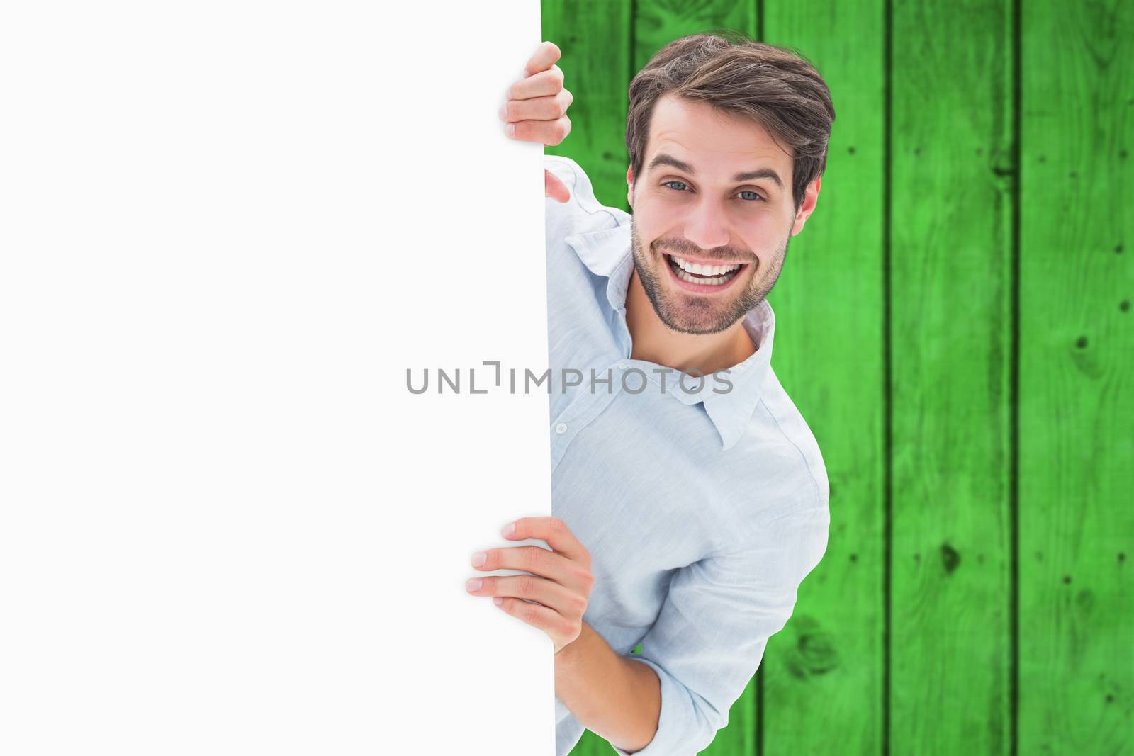 Attractive young man smiling and holding poster against bright green wooden planks