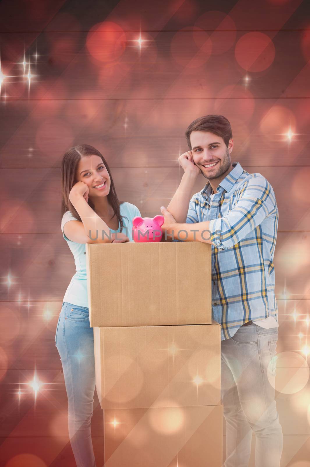 Happy young couple with moving boxes and piggy bank against light design shimmering on red