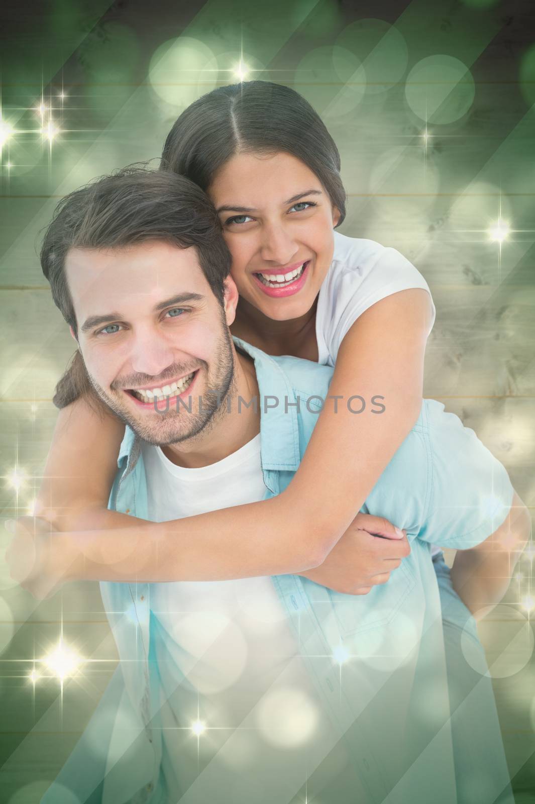 Happy casual man giving pretty girlfriend piggy back against light design shimmering on green